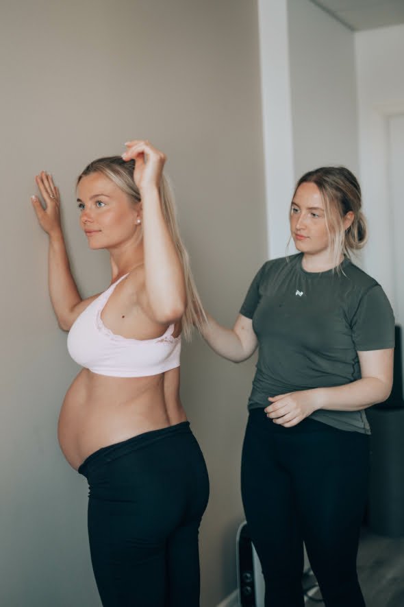 Fysioterapia raskausaikana, odottava aiti ja fysioterapeutti tekevat liiketta.