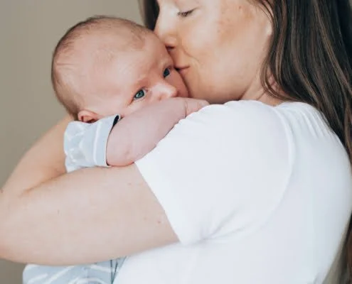 Fysioterapeutti pitää vauvaa sylissaan. Vauvan fysioterapia. Fysioterapeuttinen jalkitarkastus.