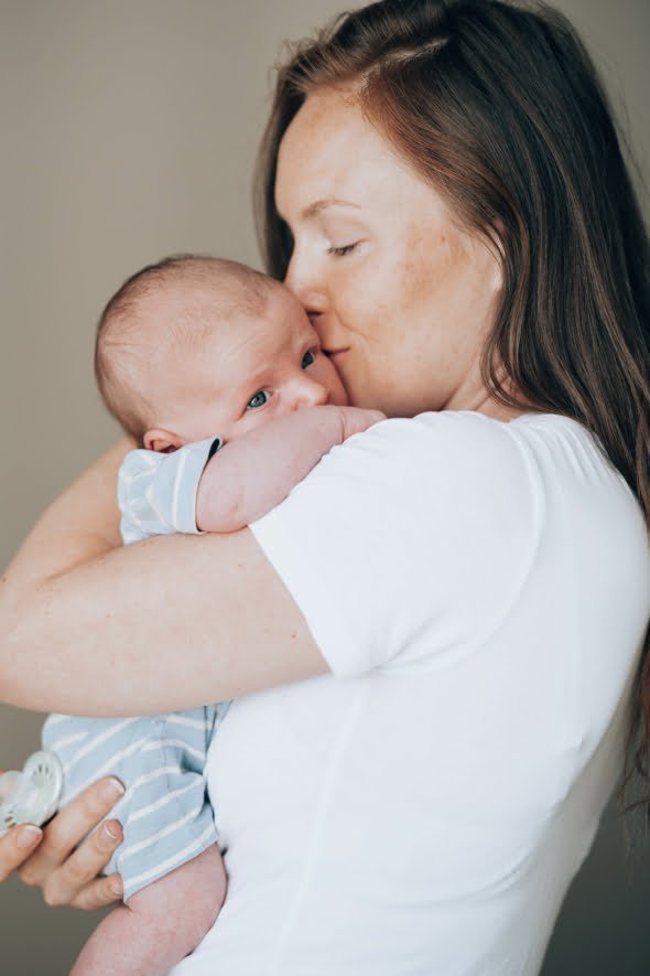 Fysioterapeutti pitää vauvaa sylissaan. Vauvan fysioterapia. Fysioterapeuttinen jalkitarkastus.