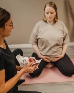 Lantiopohjan fysioterapia, fysioterapeutti nayttaa raskaana olevalle lantiomallia. Aitiysfysioterapia.