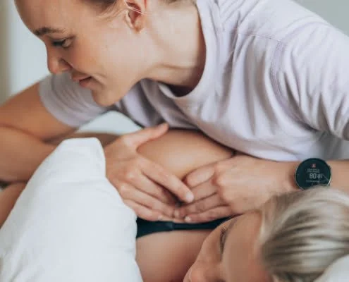 Raskaushieronta auttaa raskaana olevaa aitia. Aiti makaa kyljellaan, kun hieroja kasittelee hanta.