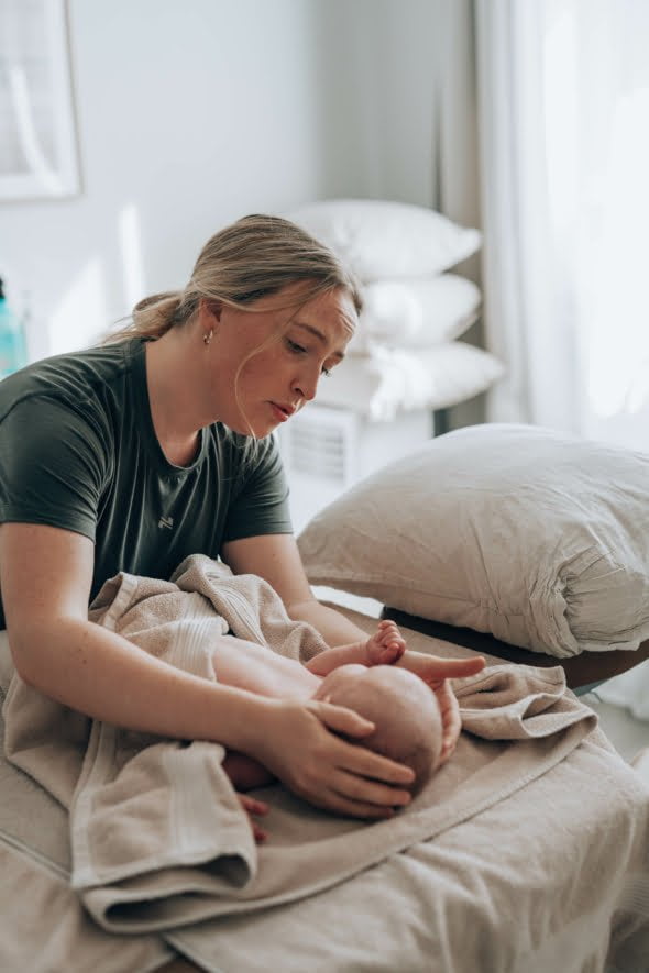 Vauvahieronta, hieroja katsoo lempeasti pienokaista.